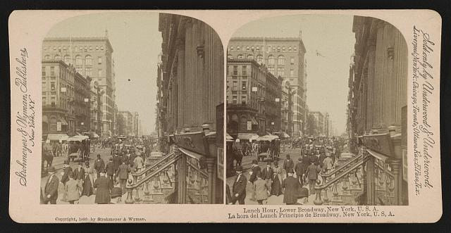 Crowded lower Broadway in New York City during lunch hour, circa 1892, with pedestrians, businesses, horses, and carts.